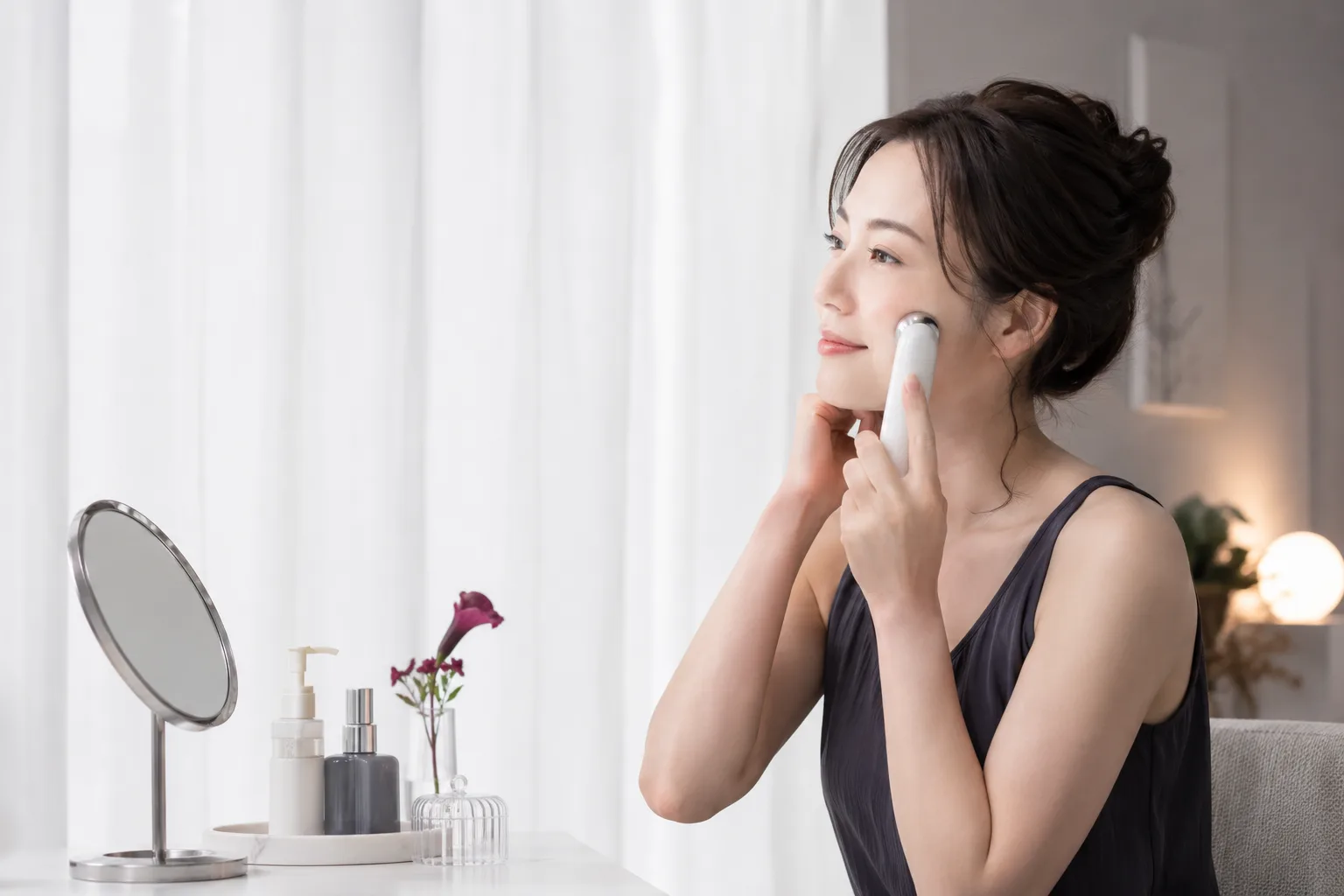 自宅で美顔器を使いながらスキンケアをする女性